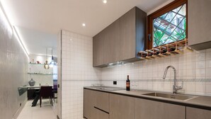 A modern kitchen with a built-in wine rack, a large window with a view, and a dining area in the background. - Ponte Rosso Modern by Mmega (Florence)