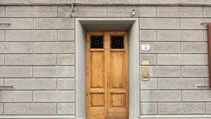 A wooden double door with a brass plate and a small window above it. - Ponte Rosso Modern by Mmega (Florence)