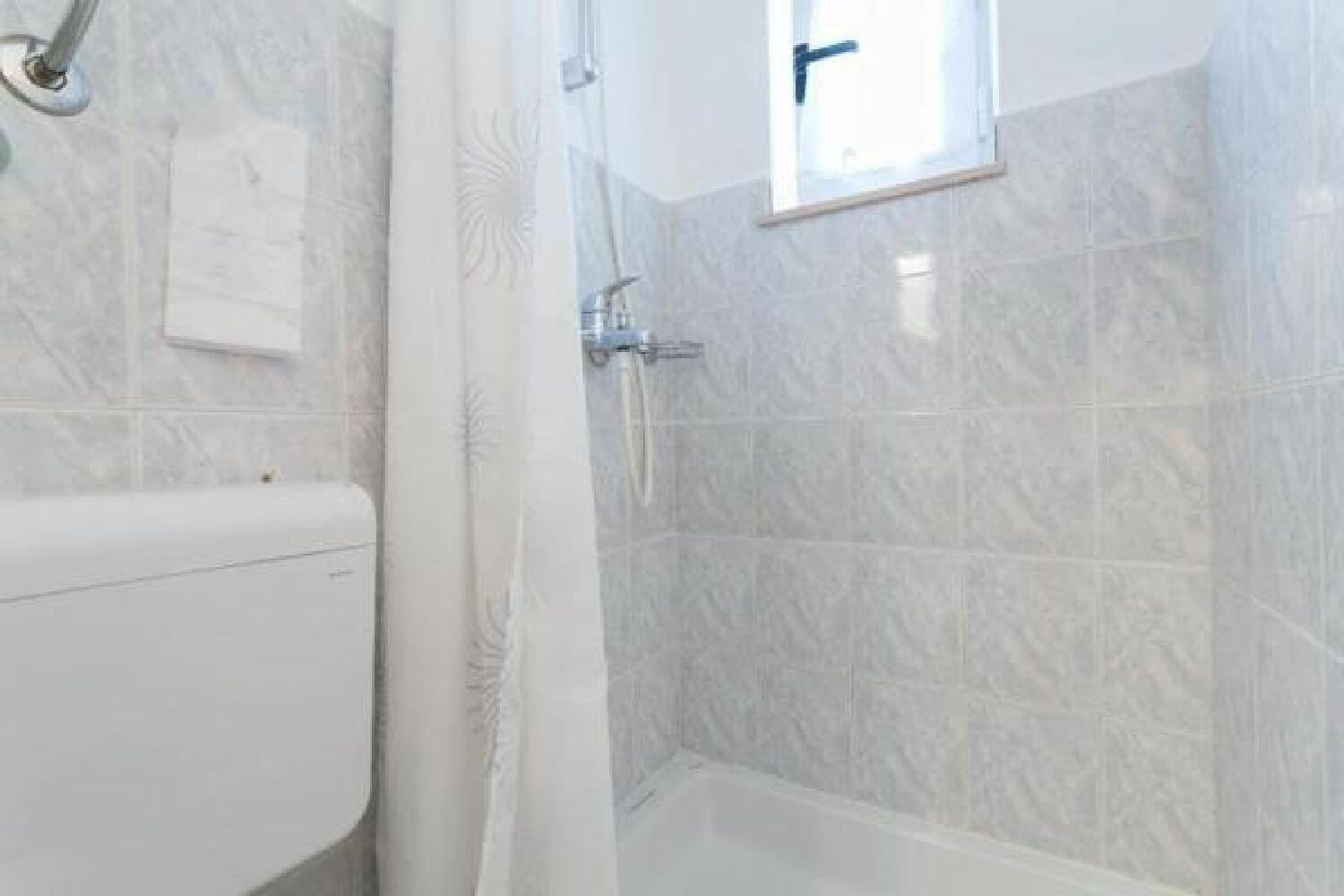 Un baño con inodoro, ducha y ventana.