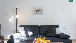 Un salon moderne avec un canapé foncé, une table d’appoint sur laquelle se trouvent des fruits et une lampe sur pied.