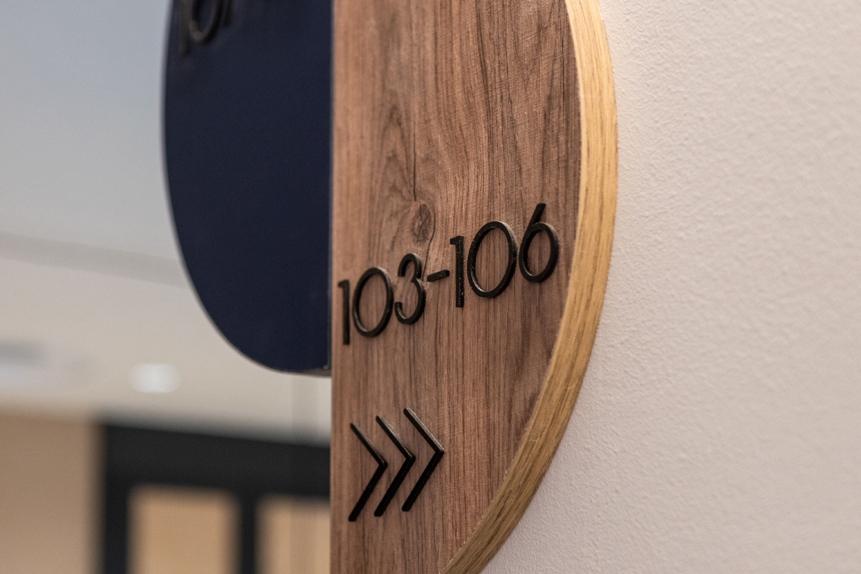 Eine hölzerne Wandtafel mit den Nummern „103-106“ und einem Pfeil.
