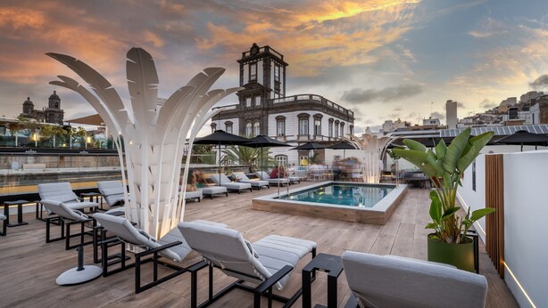 A rooftop pool area with lounge chairs and umbrellas, a pool, and a view of a historic building in the background. - Boutique Hotel Cordial La Peregrina (Las Palmas de Gran Canaria)