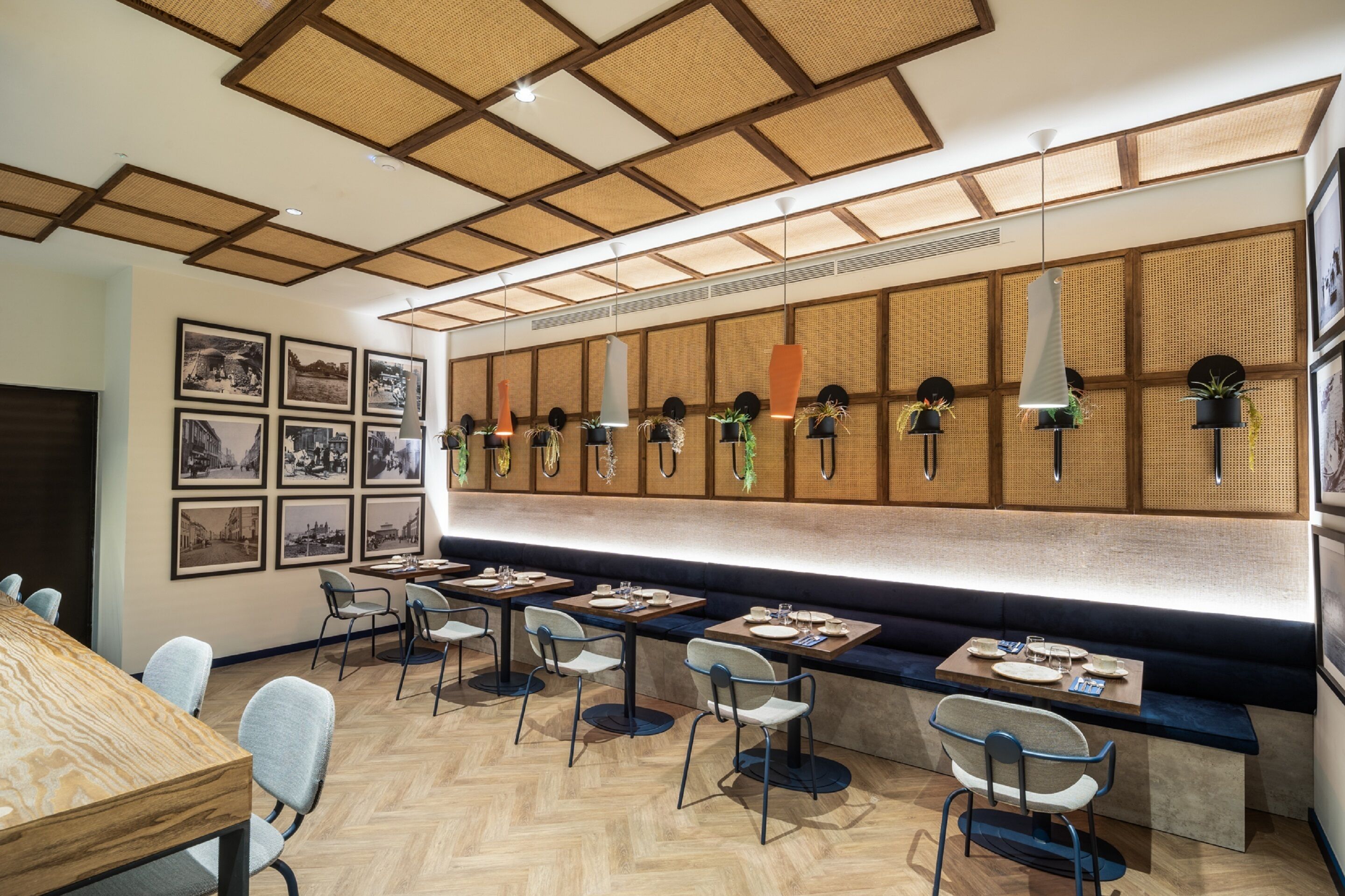 Un restaurante moderno con suelo de madera, una barra alargada con asientos y cuadros en la pared.