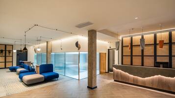 A modern interior with a reception desk, blue seating area, and a glass partition wall.