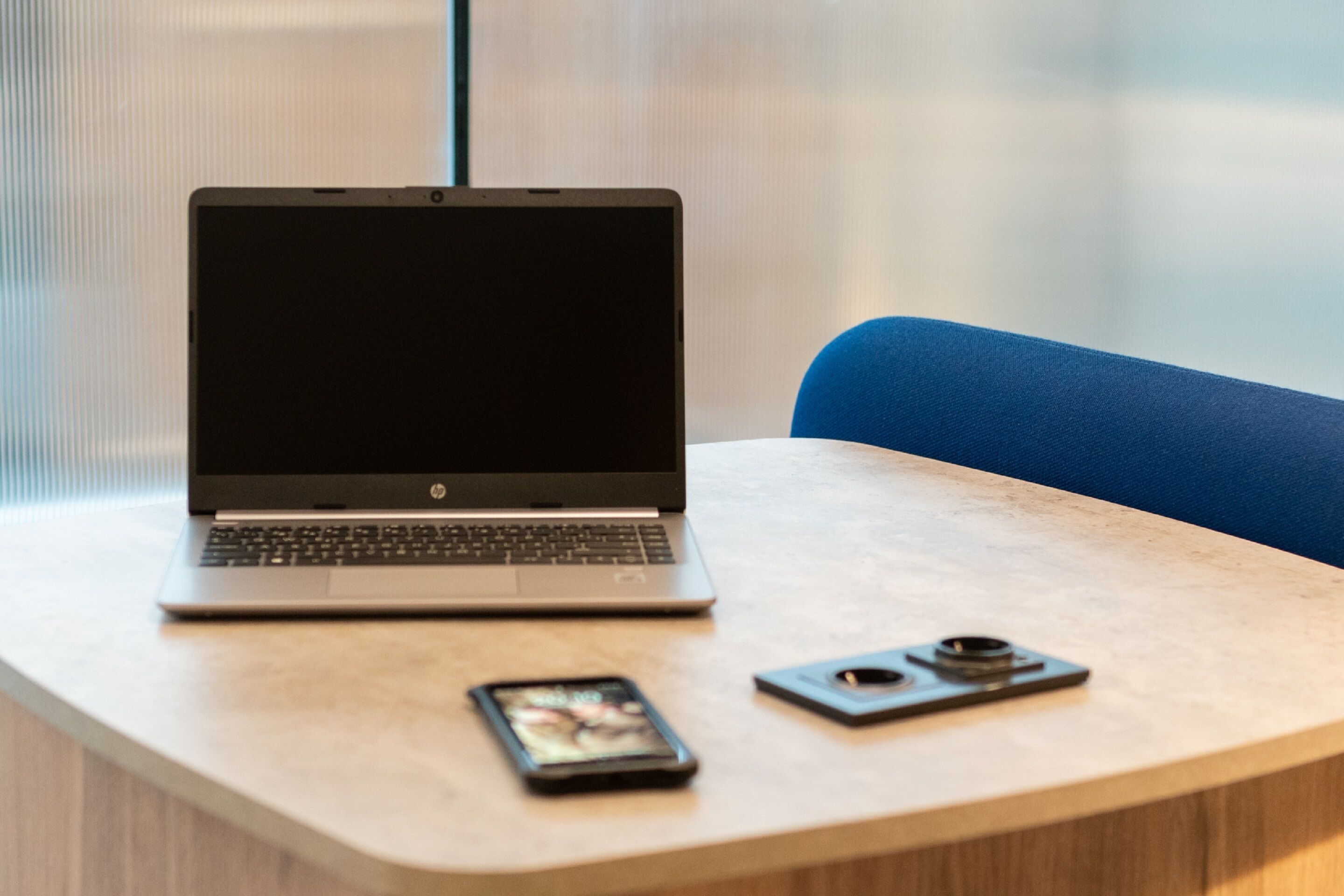 Ein Laptop auf einem Tisch mit einem Smartphone und einer Kamera.