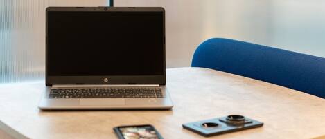 A laptop on a table with a smartphone and a camera.