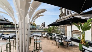 An outdoor seating area with tables and chairs, a white decorative structure, and a view of historic buildings in the background. - Boutique Hotel Cordial La Peregrina (Las Palmas de Gran Canaria)