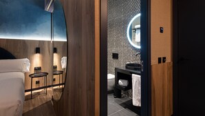 A modern bathroom with a wooden vanity, a round mirror, and a black sink. - Boutique Hotel Cordial La Peregrina (Las Palmas de Gran Canaria)