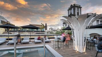 A rooftop pool area with outdoor seating and a view of a historic building.