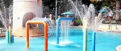 Parque acuático con múltiples chorros de agua y una piscina.