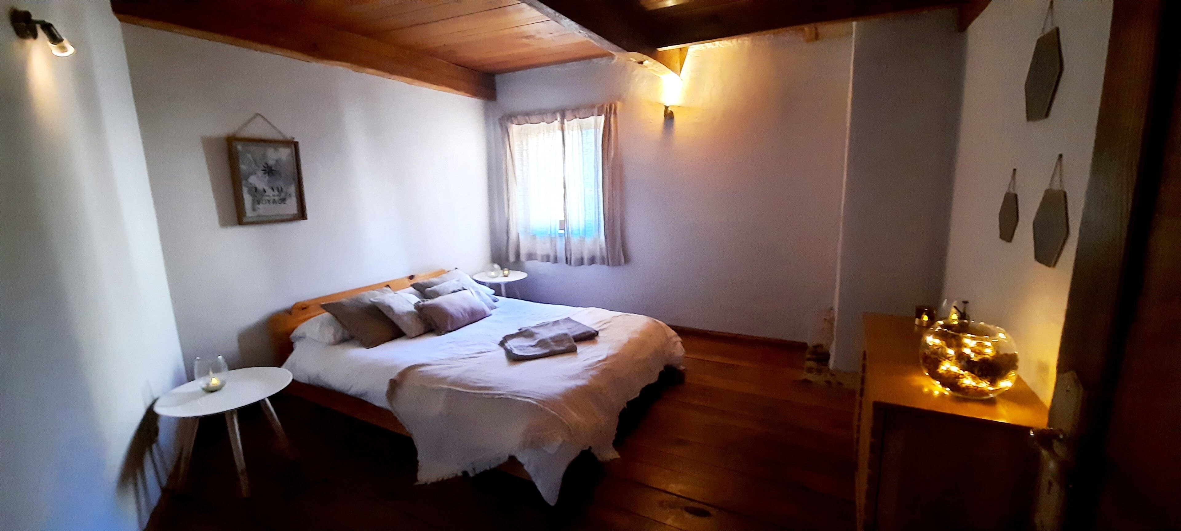 A bedroom with a bed, bedside tables, a small round table, a lamp, and a decorative item on a wooden dresser.
