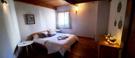 A bedroom with a bed, bedside tables, a small round table, a lamp, and a decorative item on a wooden dresser.