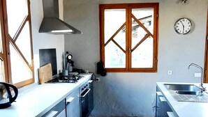 Una cucina con piano cottura a gas, cappa aspirante, lavello e finestra vista.