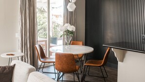 Un espace repas moderne avec une table ronde, quatre chaises et un vase rempli de fleurs blanches.