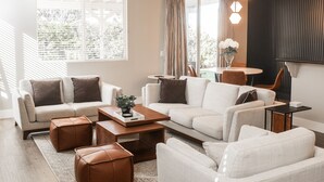 Un salon moderne comprenant un ensemble de canapés, une table basse, des poufs et un coin repas avec une table et des chaises.