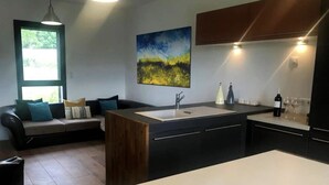 A modern kitchen with a central island, a dining area with a bench, and a large window providing natural light.