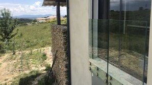 A room with a large window overlooking a grassy landscape with distant hills.