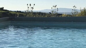 A swimming pool with a tiled edge and a view of distant hills.