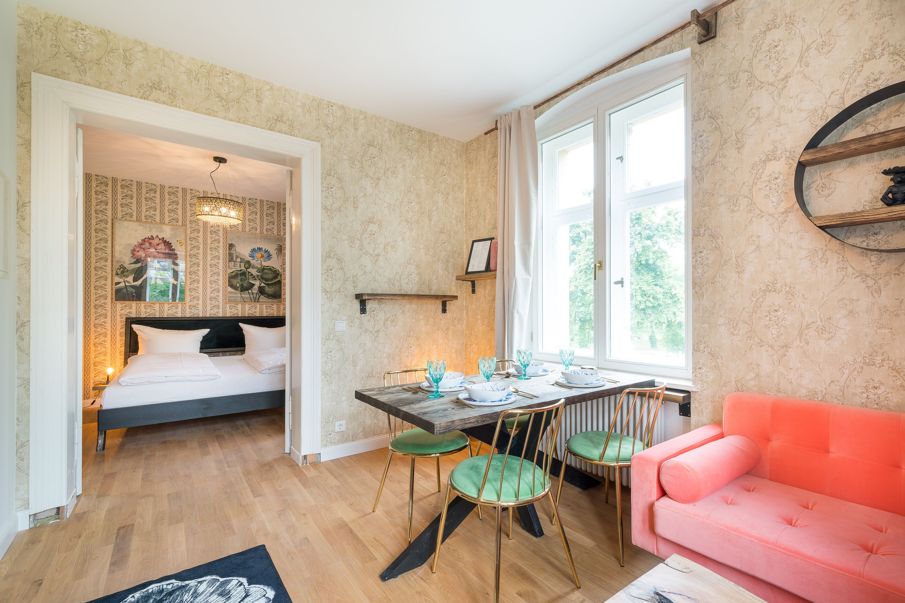 Een slaapkamer met een bed, een eettafel met stoelen en een roze bank.