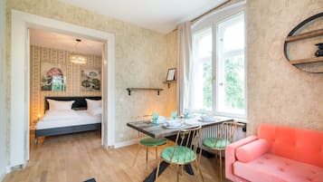Een slaapkamer met een bed, een eettafel met stoelen en een roze bank.