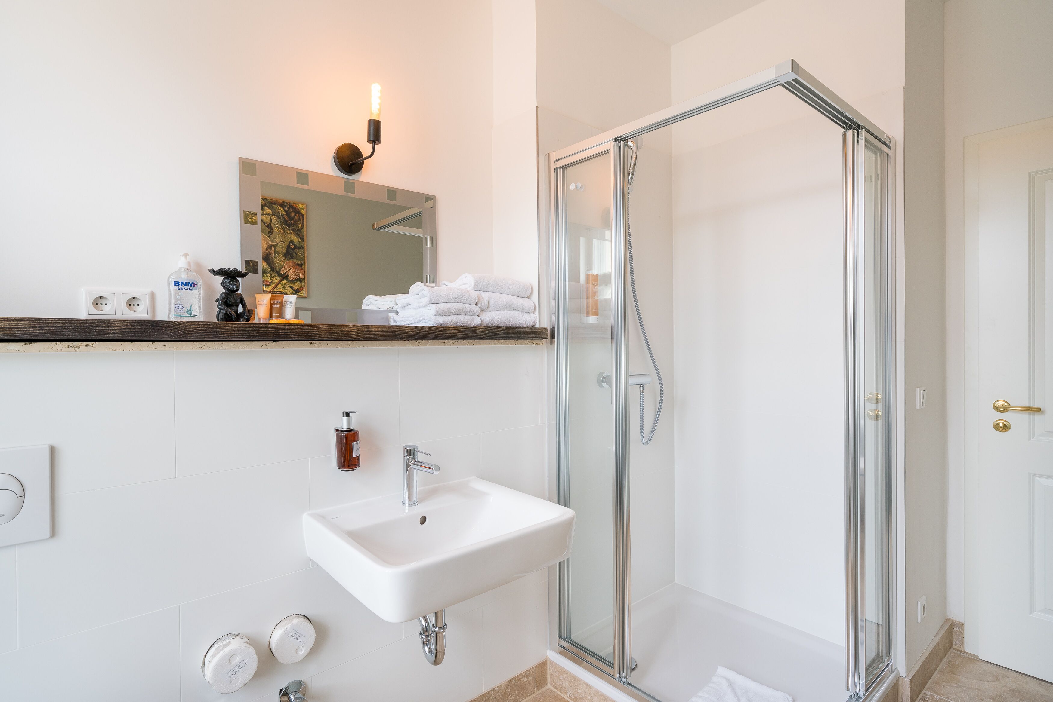 Une salle de bain moderne avec une douche à parois de verre, un lavabo blanc et un miroir au-dessus du lavabo.