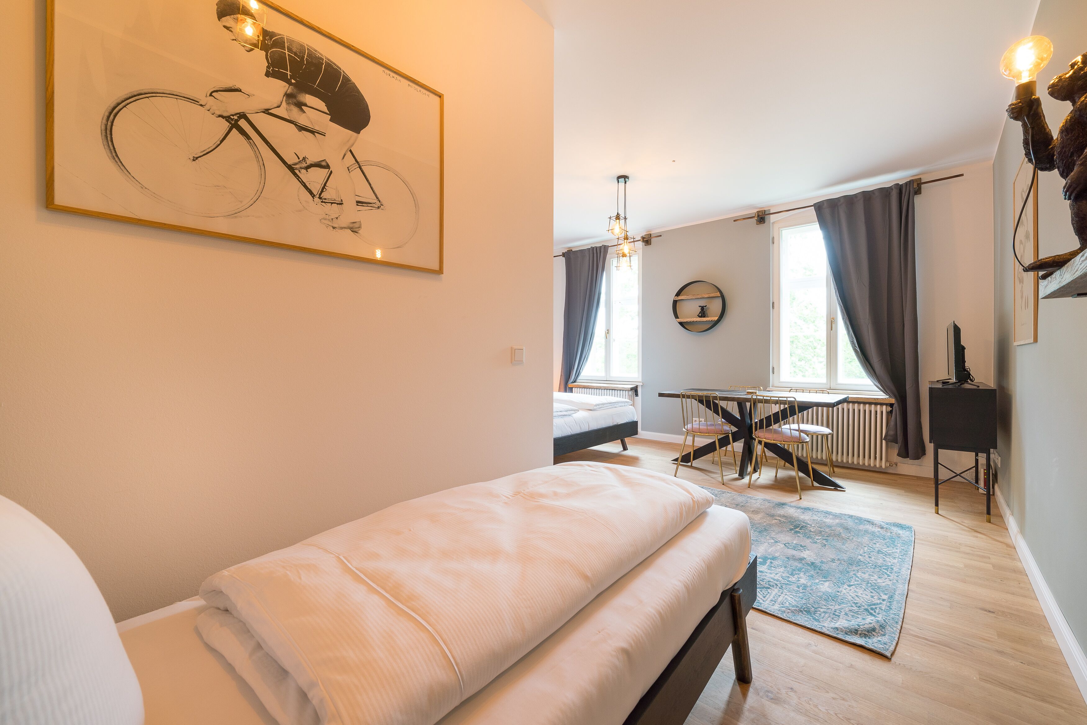 Ein modernes Schlafzimmer mit einem großen Bett, einem Schreibtisch und einem Kunstwerk mit Fahrradmotiv an der Wand.
