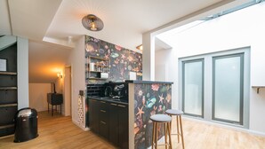 Una cocina moderna con encimera negra, taburetes de madera y un mural decorativo.