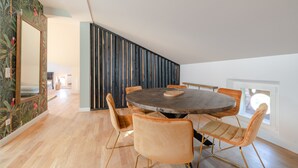 Un comedor moderno con una mesa redonda y seis sillas, un espejo grande y una pared de listones de madera.