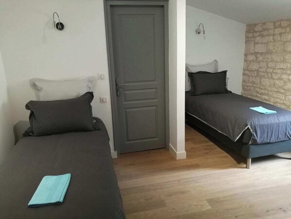 Ein Zimmer mit zwei Betten, einer Tür und einer Steinwand.