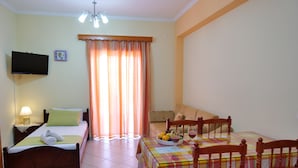 A room with a bed, a table with a fruit bowl and glasses, a television, and a window with curtains. - Remarkable 2-bed Apartment in Sarandë (Sarandë)