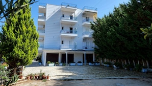 A multi-story building with balconies, a covered entrance, and potted plants. - Remarkable 2-bed Apartment in Sarandë (Sarandë)
