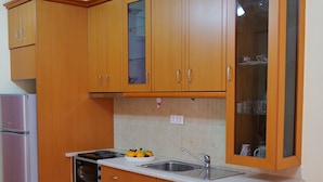 A compact kitchen with wooden cabinets, a built-in oven, a refrigerator, and a sink. - Remarkable 2-bed Apartment in Sarandë (Sarandë)