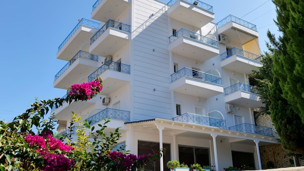 A multi-story hotel with balconies, a covered entrance, and surrounding greenery. - Remarkable 2-bed Apartment in Sarandë (Sarandë)