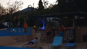 A swimming pool with lounge chairs and a person lying on the edge. - Charming 4-bed House in Pyrgetos (Tempi)