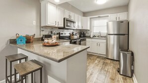 A modern kitchen with white cabinets, stainless steel appliances, and a central island with stools.