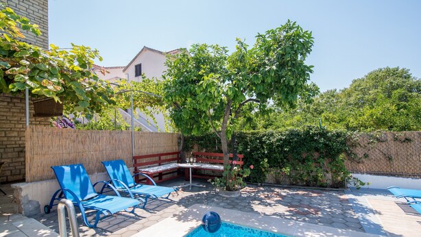 Une piscine aux carreaux bleus, entourée de chaises longues et d’une terrasse en bois.