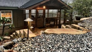 Eine rustikale Holzhütte mit überdachter Veranda, Steinstufen und einer Schotterauffahrt.
