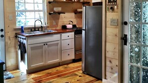 Eine Holzhütte mit einer Küche, die einen Kühlschrank, ein Waschbecken und Holzschränke enthält.