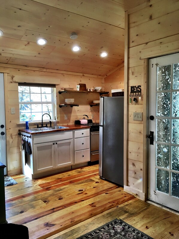 Cocina de cabaña de madera con refrigerador, pileta y alacenas de madera.