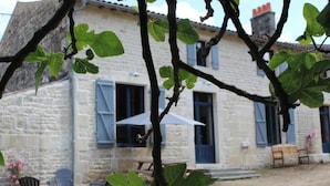 Un bâtiment en pierre doté d’un balcon et d’une table avec des chaises à l’extérieur.
