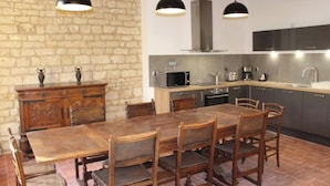 Une cuisine rustique avec un mur en pierre, une table à manger en bois et des appareils électroménagers modernes.