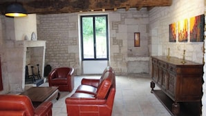 Une pièce aux murs de pierre, avec une cheminée, des canapés en cuir et un meuble en bois.