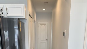 Una cocina con un refrigerador de acero inoxidable, piso de madera y muebles de color blanco.