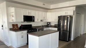 Una cocina moderna con armarios blancos, electrodomésticos de acero inoxidable y una isla central.