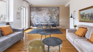 Una sala de estar moderna con un sofá gris, una mesa redonda de centro y un comedor con mesa y sillas.