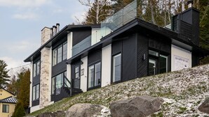 Een modern gebouw met twee verdiepingen, een gevel van natuursteen, grote ramen en een bord waarop staat dat het een hotel is.