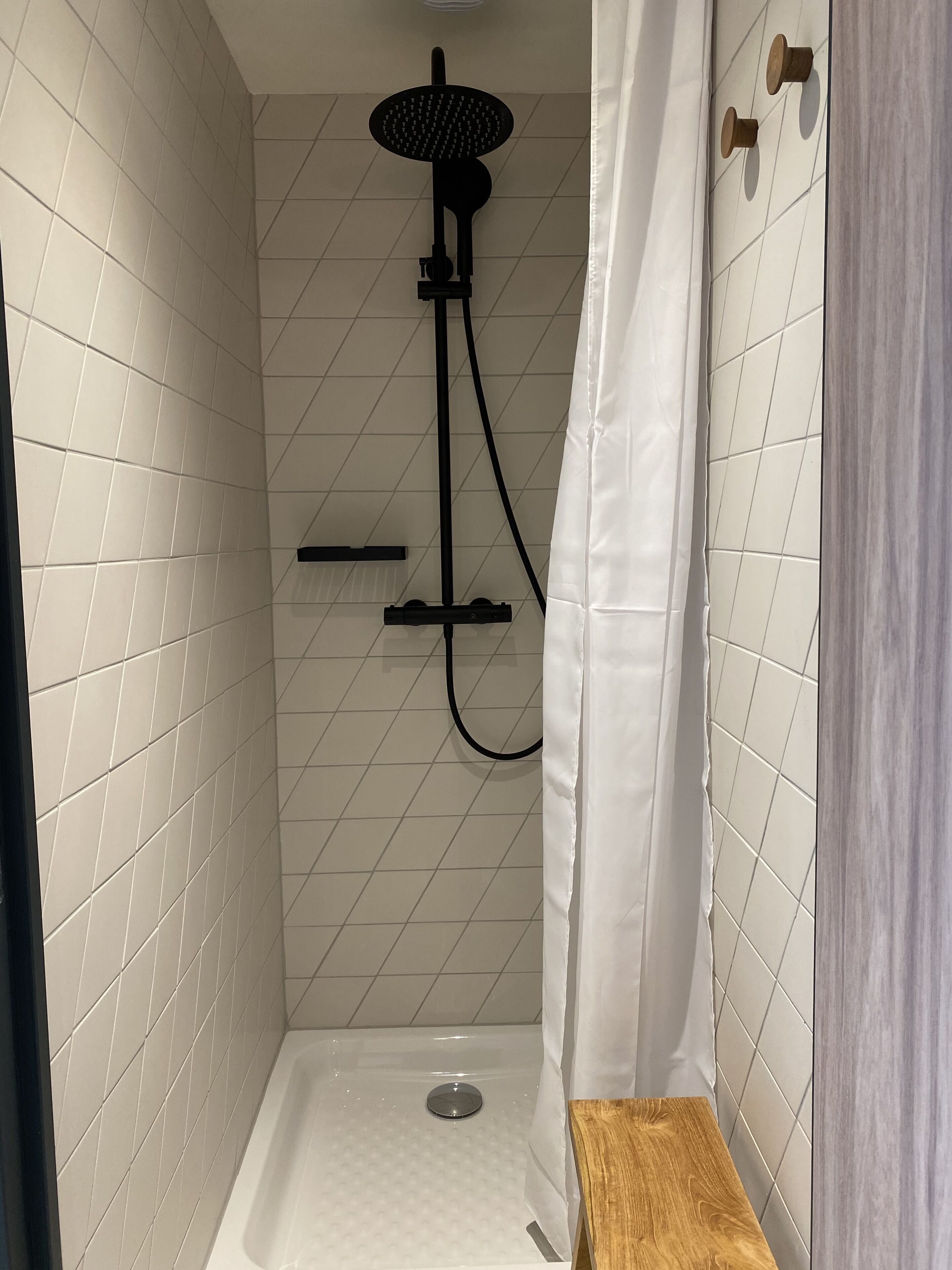 A small, tiled shower area with a handheld showerhead and a wall-mounted faucet.
