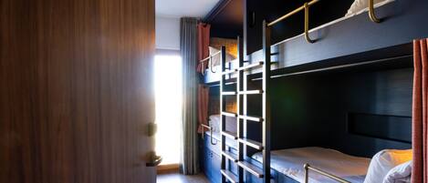 Dormitorio con literas, puerta de madera, luminaria y cortina.