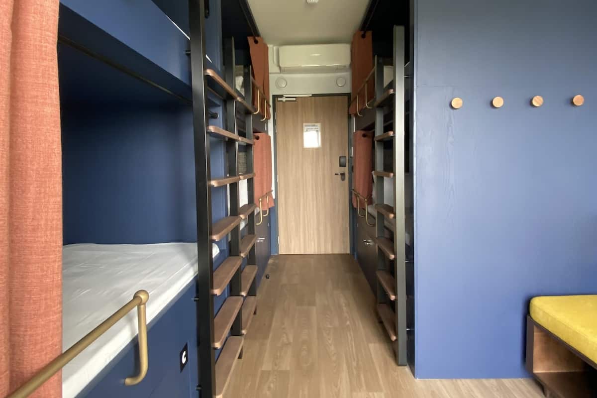 A narrow hallway with bunk beds on either side, a wooden floor, and a door at the end.