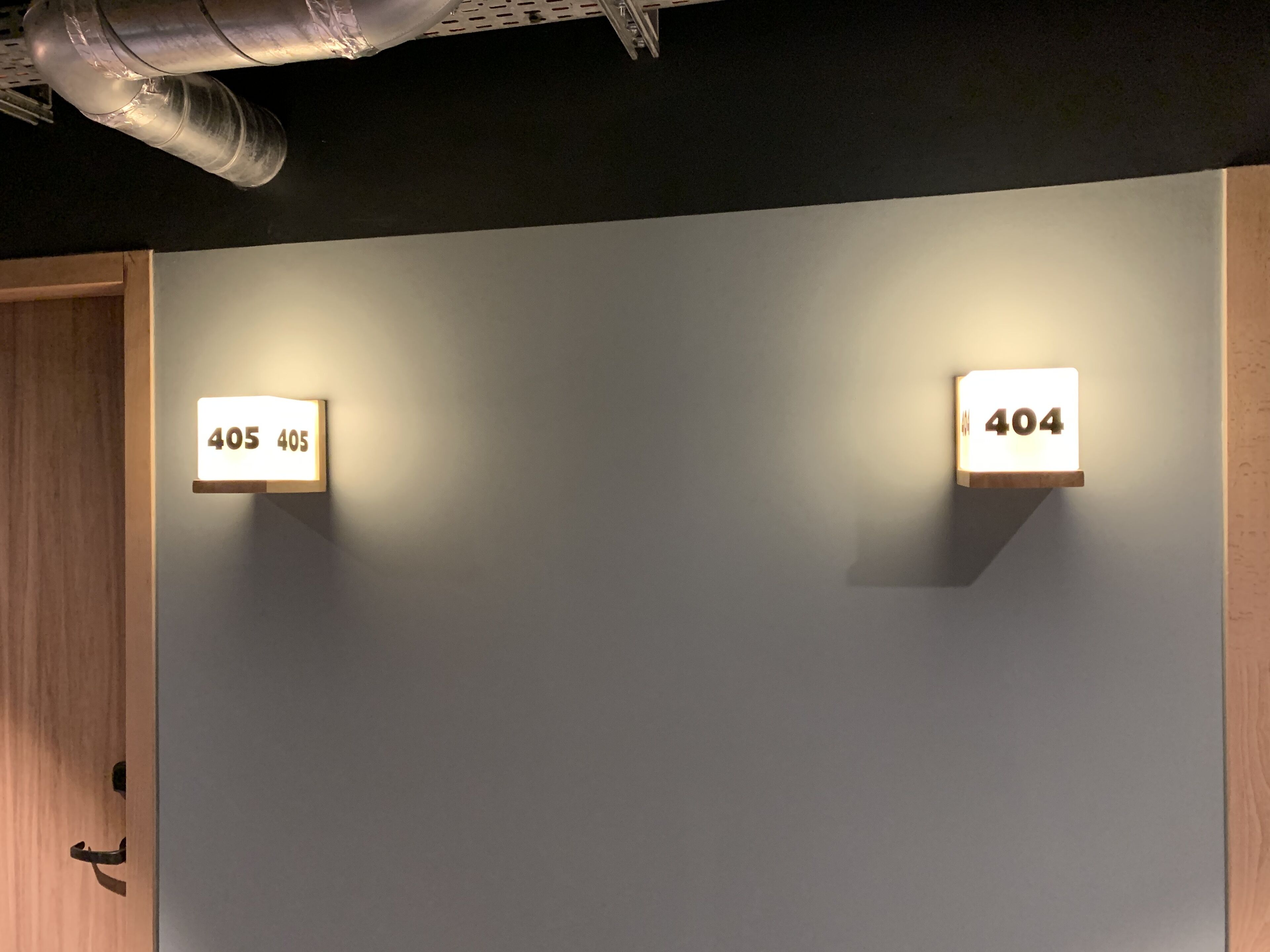 Two illuminated room numbers, 405 and 404, on a plain wall.